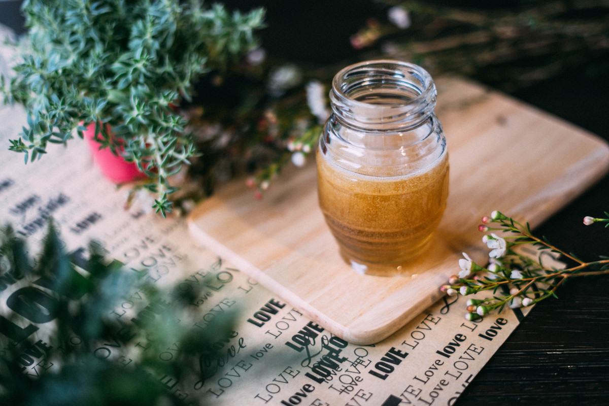 shallow focus photo of a glass jar with honey on a chopping board