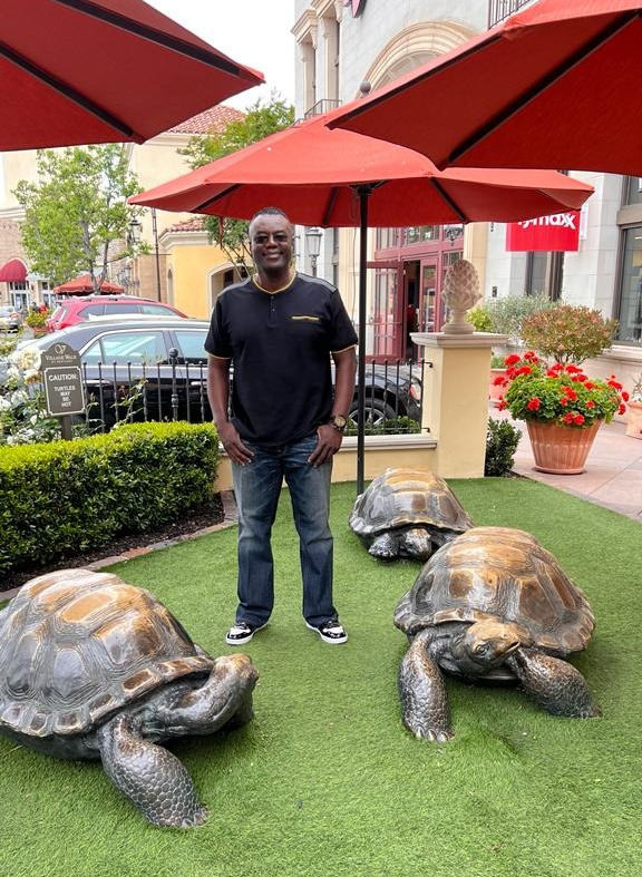 Photo of a man outside a store next to turtle statues.