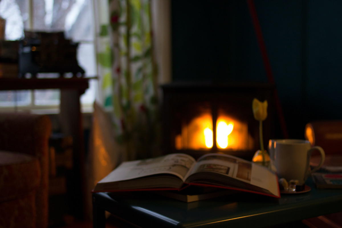 a study with table and book on top, a fire in the background